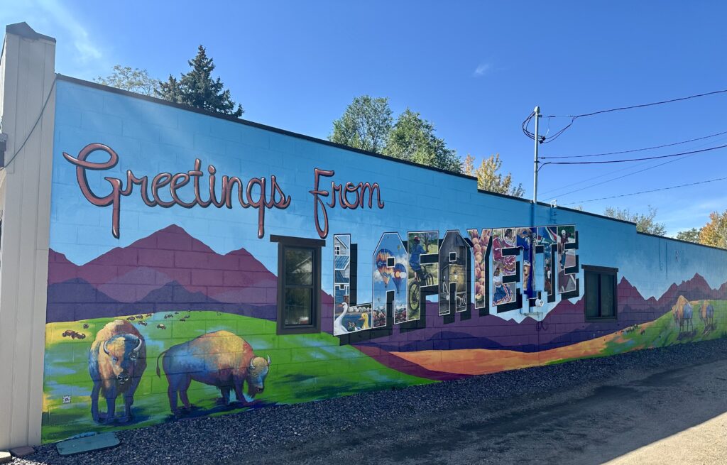 Greetings from Lafayette mural with mountains and bison. Local imagery painted inside of the letters.